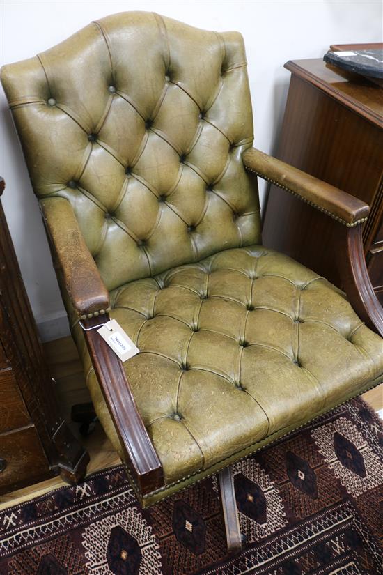 A mahogany open arm elbow swivel desk chair upholstered in buttoned green hide